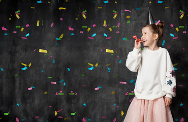 Little girl laughs and has fun at a celebration on the background of a school board and confetti with a free place on the left