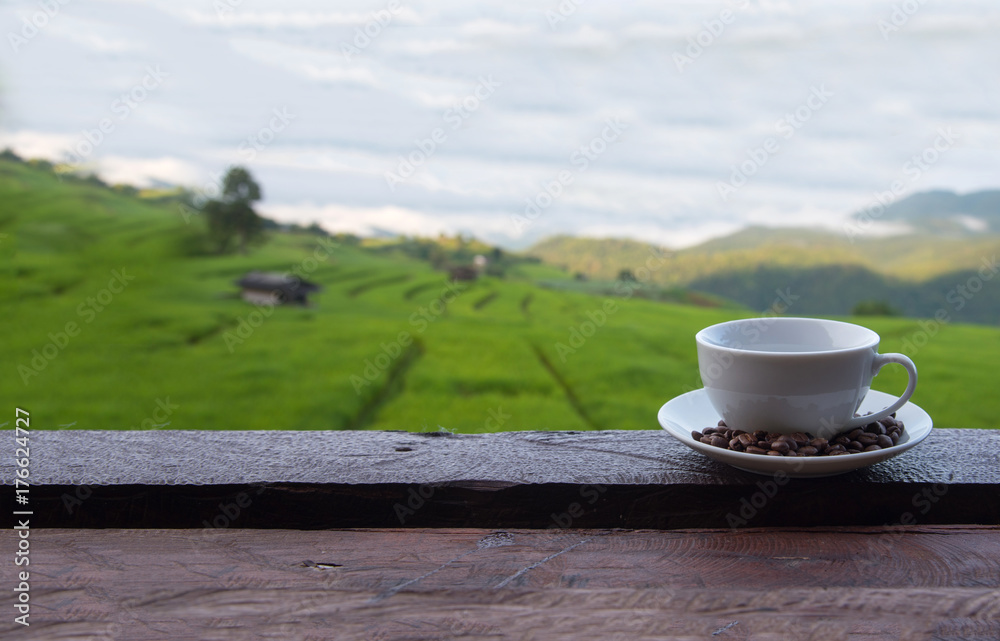 A white cup of hot coffee and coffee beans put interspersed in dish on wood table with green rice field background,wallpaper
A white cup of hot coffee and coffee beans put interspersed in dish on wood table with green rice field background,wallpaper