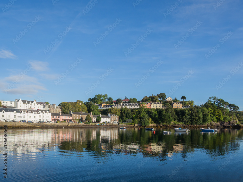 Fototapeta premium View across the harbour of Portree on the Isle of Skye, Scotland with reflection in water on a beautiful summers day.