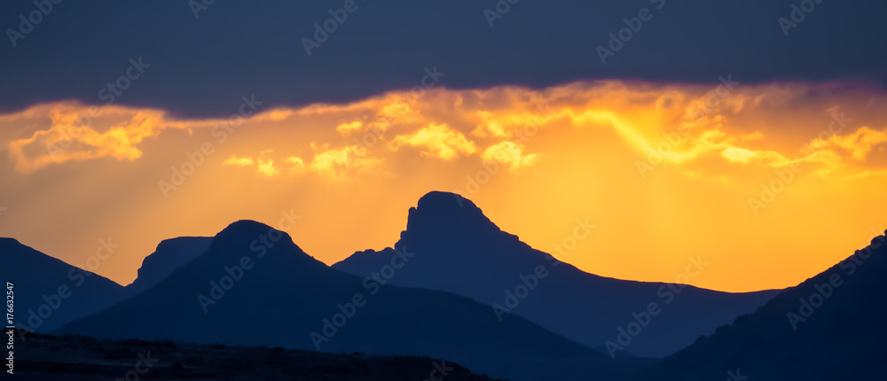 Dramatic yellow orange sunset over mountains with storm clouds, Lesotho, Southern Africa