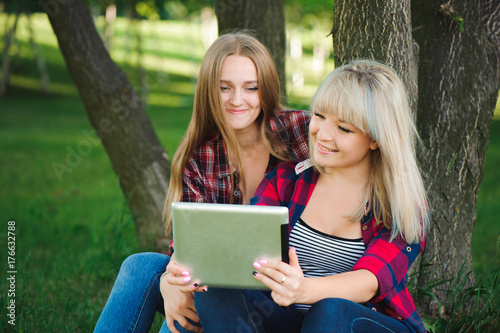 Smiling women using tablet ps on a green meadow
