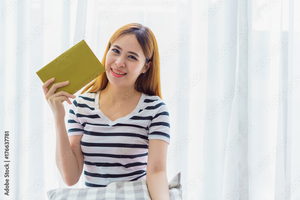 Beautiful young woman reading book in the living room near window at home. concept of relax on holiday. Beautiful young woman reading book in the living room near window at home. concept of relax on holiday.