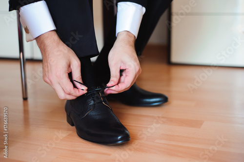Business man tying shoe laces on the floor. Close-up.
