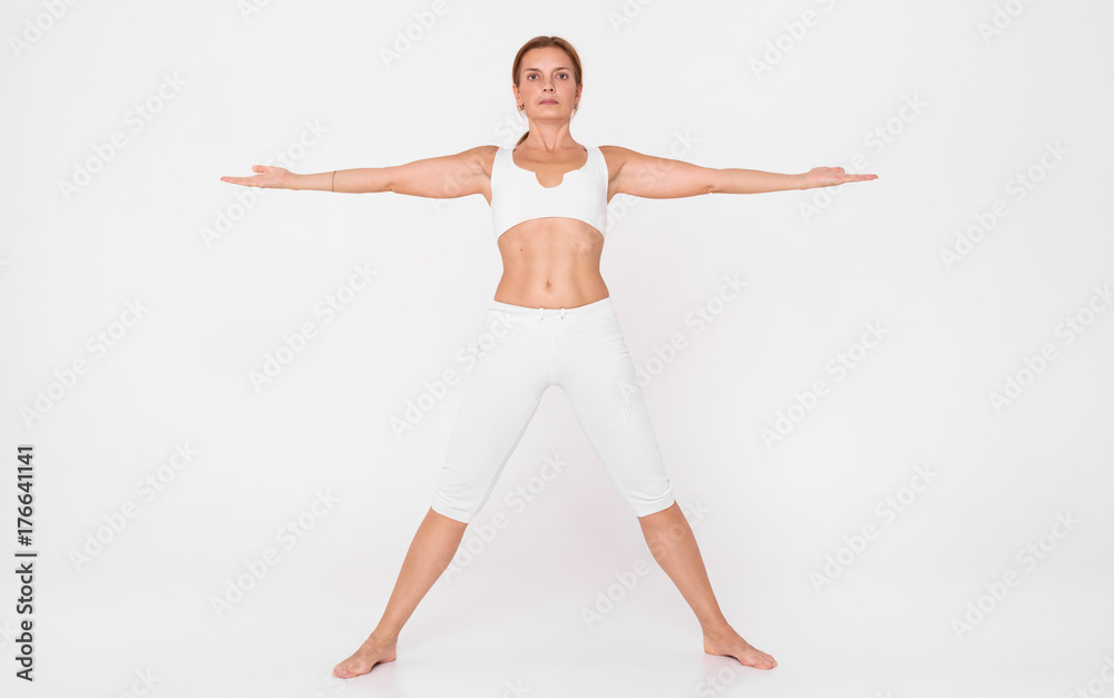 An adult woman doing yoga in a white hall.