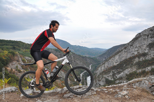 Young man riding a bike on rocks on the mountain, extreme riding bicycle off road on rocks
