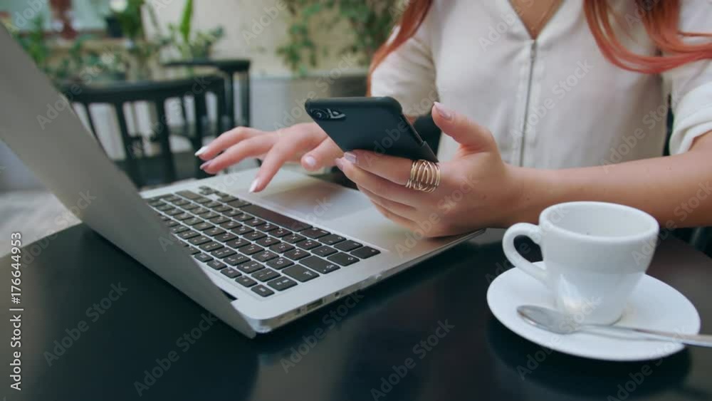 A beautiful girl using her mobile phone and a laptop in the room. Closeup shot. Soft focus.
