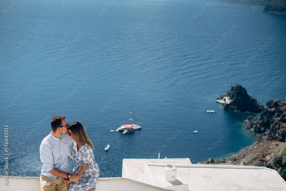 Happy couple hugging and laughing together with a view of Santorini Happy couple hugging and laughing together with a view of Santorini