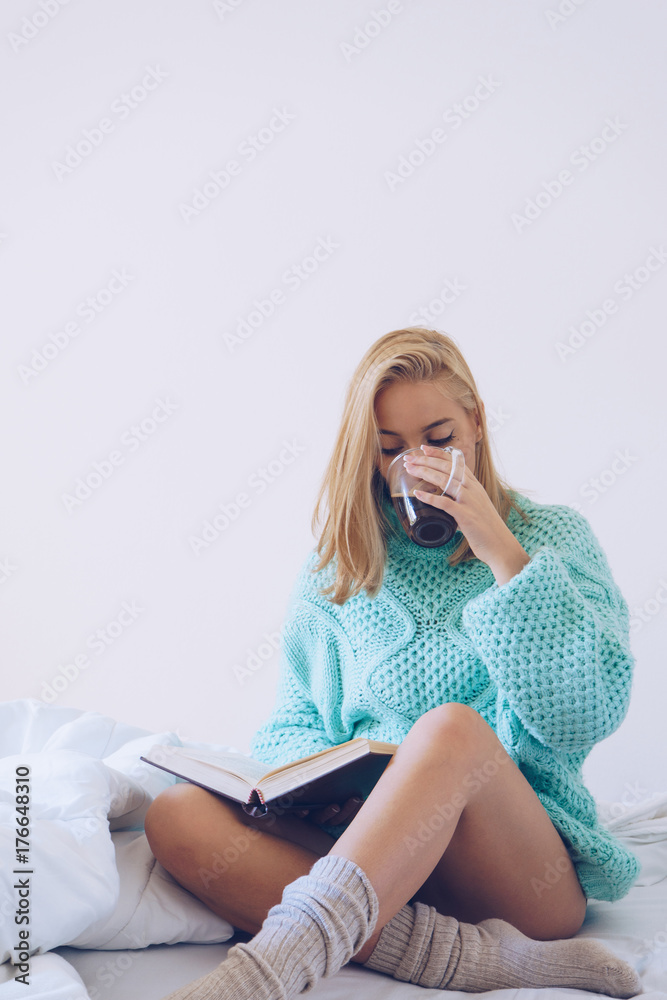 Young woman sitting in bed while reading a book Young woman sitting in bed while reading a book