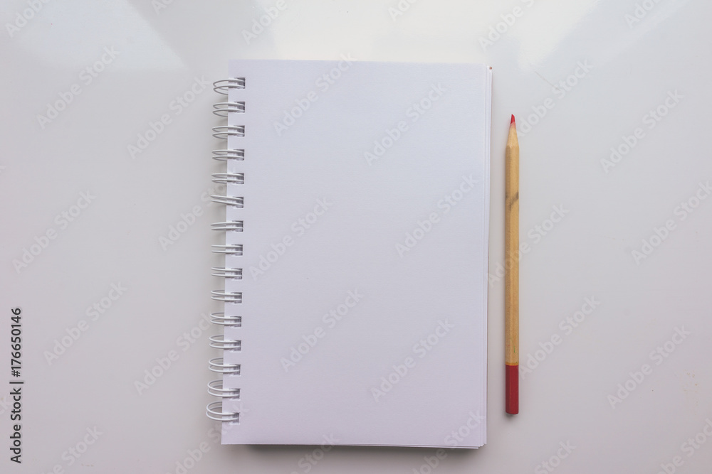 Open Notepad with a blank sheet of paper and a pencil on a white background. Top view Open Notepad with a blank sheet of paper and a pencil on a white background. Top view