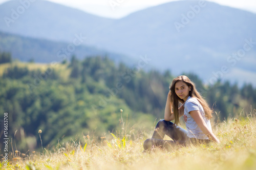 Young girl is sitting on the mountainside