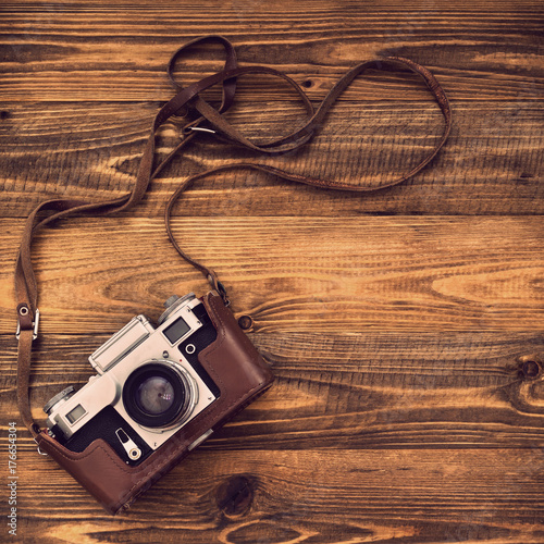 Old retro camera on vintage rustic wooden planks boards. Education photography courses back to school concept abstract background. Close up, top view, copy space.