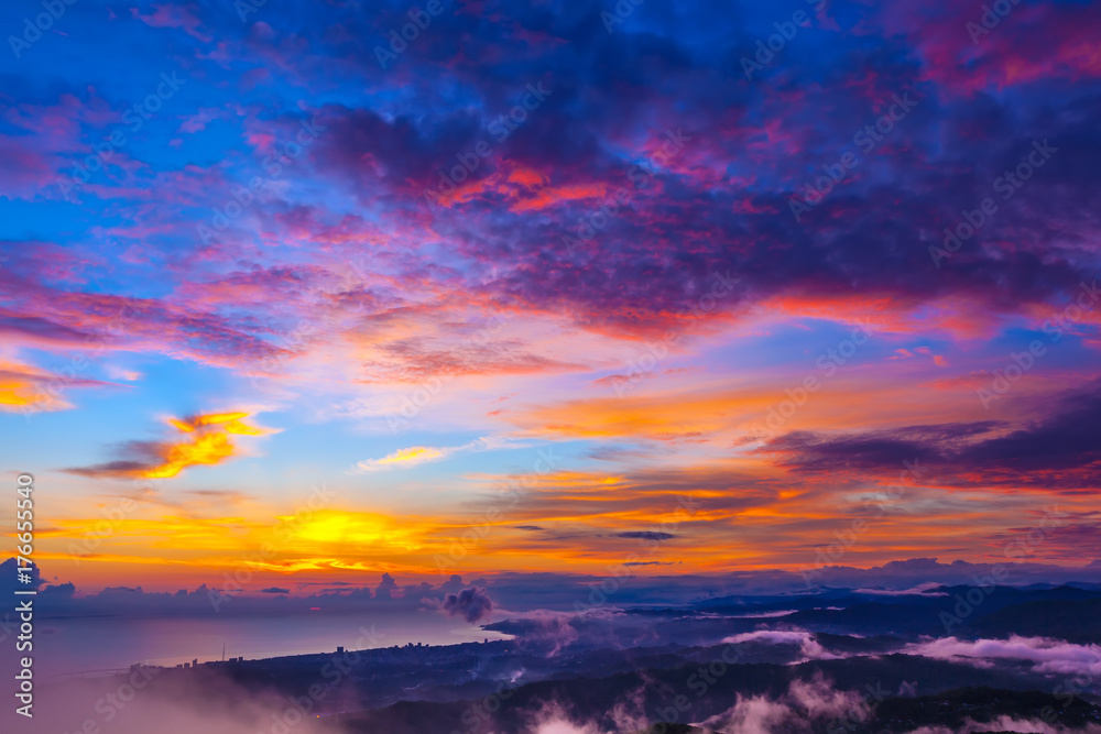 Incredible colorful sunset on the seashore, hills and mountains under clouds of different colors. Big Sochi, Russia.