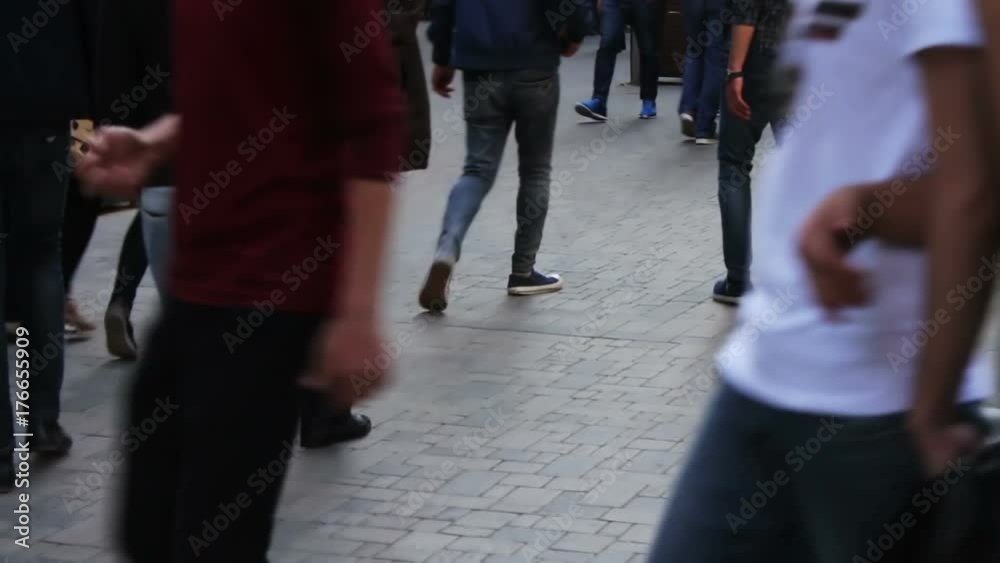 Feet of people passing by. The crowd is walking along the street Feet of people passing by. The crowd is walking along the street