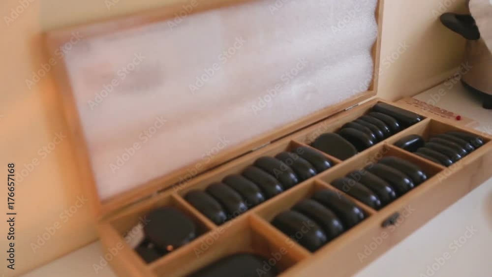 The masseur opens a box of stones and puts them in the heater The masseur opens a box of stones and puts them in the heater