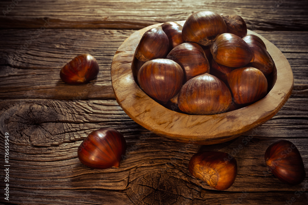 fresh chestnuts in a bowl on wooden background fresh chestnuts in a bowl on wooden background