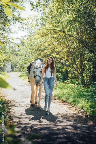 Fototapeta Naklejka Na Ścianę i Meble -  Girl teenager and white horse in a park in a summer