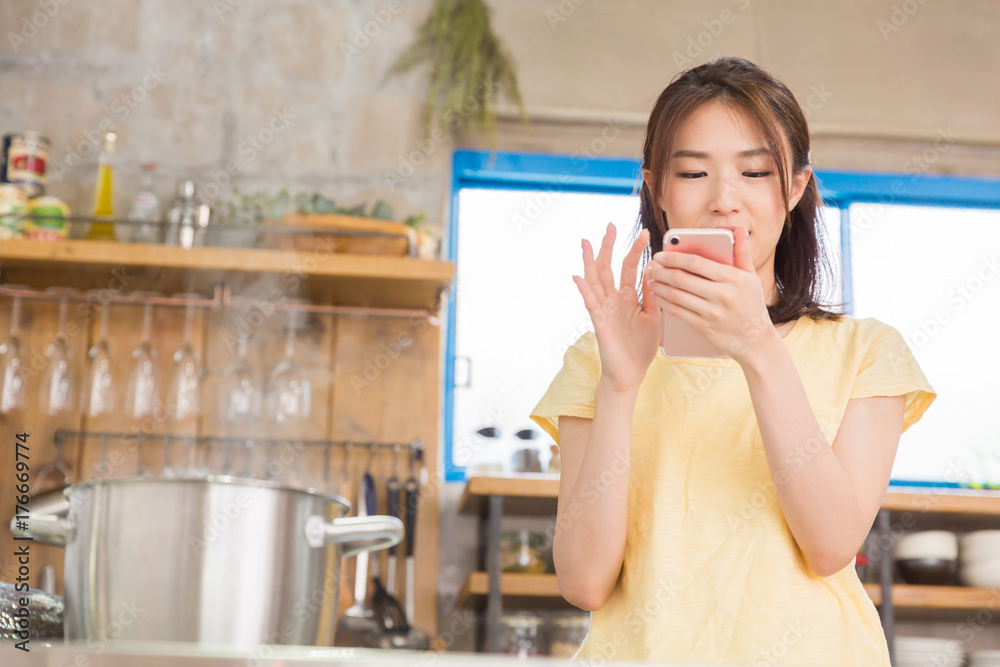 キッチンでスマホを見る女性 キッチンでスマホを見る女性