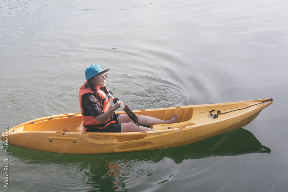 young woman in orange life jackets kayaking on a lake. Happy young woman canoeing in waterpark