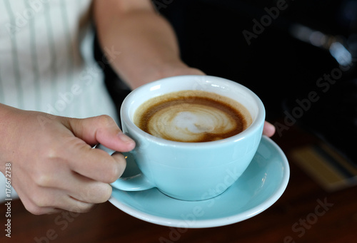Woman hands holding green coffee cup at cafe background, close up, food and drinks concept