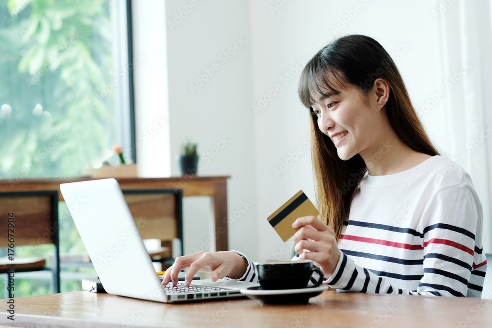 Young asian woman holding credit card and using laptop computer to shopping on line at cafe, business and technology concept, digital marketing, casual lifestyle Young asian woman holding credit card and using laptop computer to shopping on line at cafe, business and technology concept, digital marketing, casual lifestyle