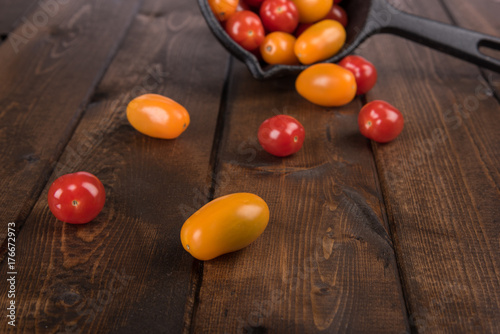 Fototapeta Naklejka Na Ścianę i Meble -  Farm Fresh Red and Orange Cherry Tomatoes Pouring Out of Cast Iron Pot