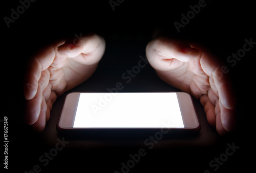 white light from the smartphone reflect your hand at night in the dark.blank screen for text and design photo