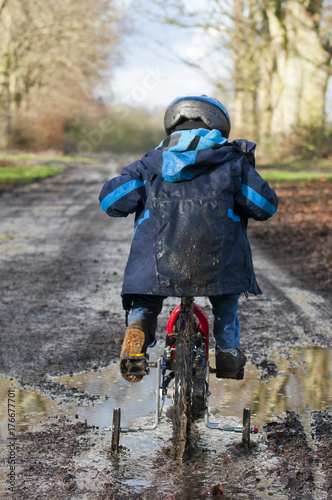 Boy cycling through muddy puddle