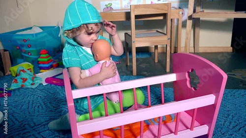 Adorable child dandle swing doll baby near toy crib bed