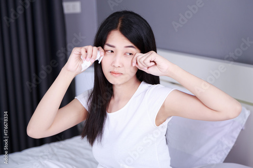 woman is crying on bed in bedroom