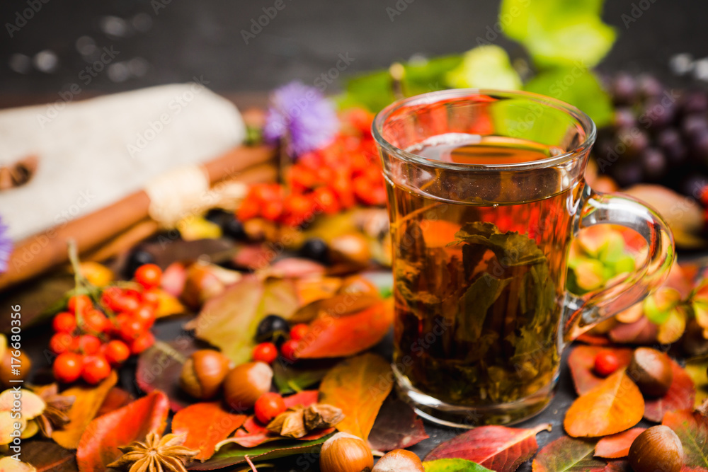 Cup of tea with autumn leaves, nuts, berries and spices on the rustic background. Shallow depth of field. Cup of tea with autumn leaves, nuts, berries and spices on the rustic background. Shallow depth of field.