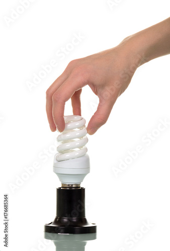 Female hand screwing fluorescent light bulb into the cartridge is isolated on white.