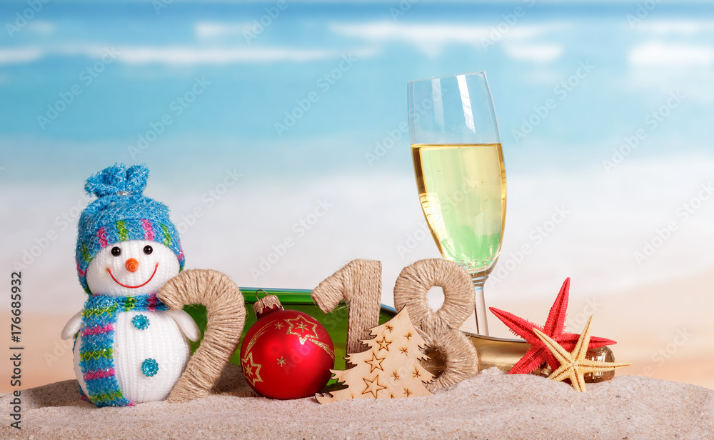 New Year inscription 2018, ball instead number 0, bottle and glass champagne, snowman, Christmas tree, starfish in sand.