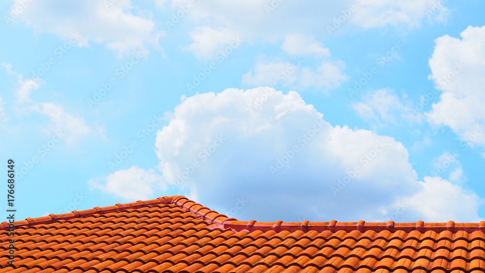 Bright light blue sky with many white and grey chunks of clouds floating background, with red brown concrete wavy corrugated roof as the lower border Bright light blue sky with many white and grey chunks of clouds floating background, with red brown concrete wavy corrugated roof as the lower border