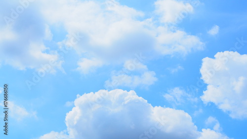 Bright light blue sky with many white and grey chunks of clouds floating background, wide screen