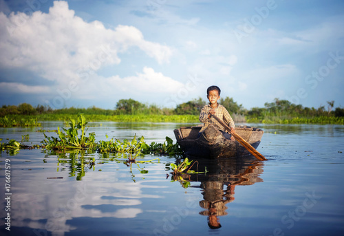 Cambodian boy traveling by boat in his floating village.