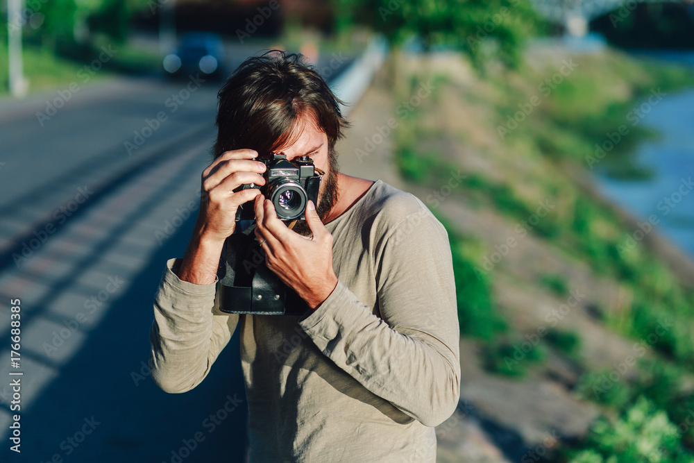 Casual hipster man making photo using retro camera outdoors in the park Casual hipster man making photo using retro camera outdoors in the park