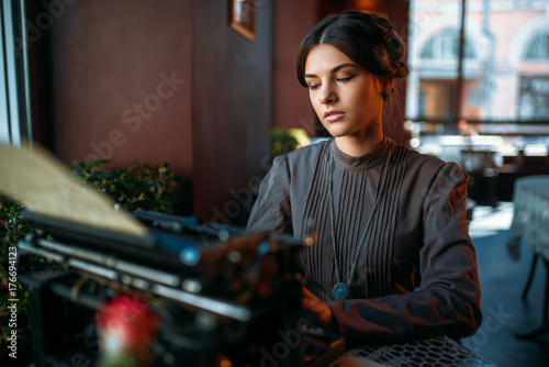 Serious lady prints on ancient typewriter