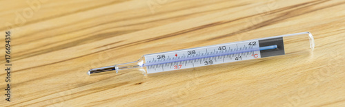 Clinical thermometer on wooden table, banner