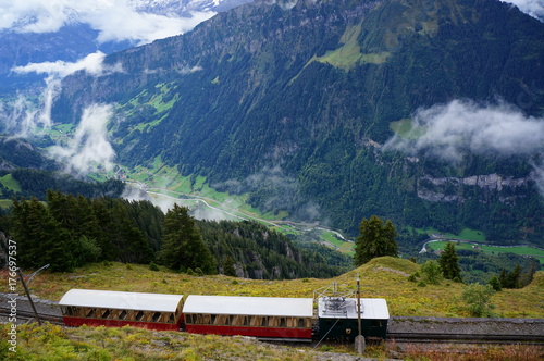 Retro train from Interlaken to Schynige Platte and stunning view of alpine forest, mountain range and mist as background. Switzerland
