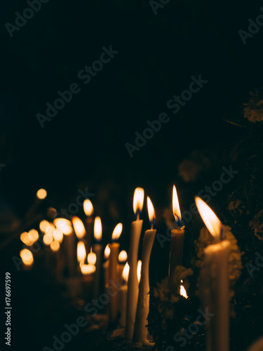 Many burning candles light in dark night