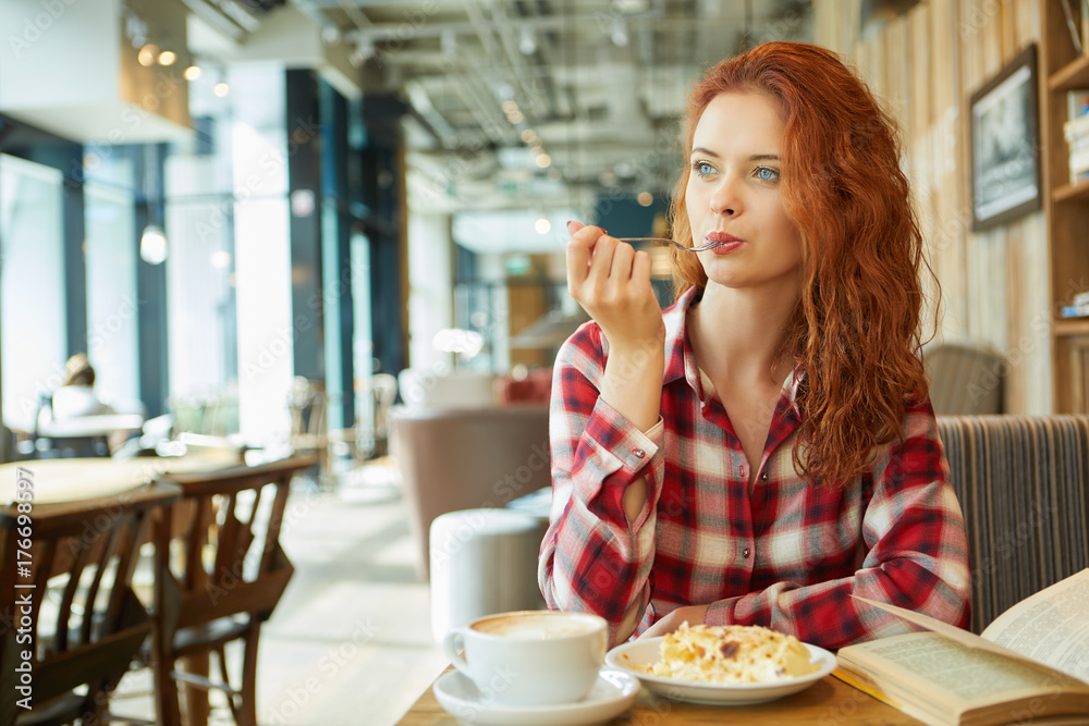 Young  beautiful woman in glasses reading interesting book in cafe