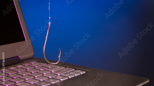 fish hook hanging above a laptop keyboard