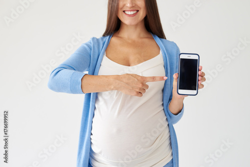 Pregnant woman pointing at smartphone with black screen