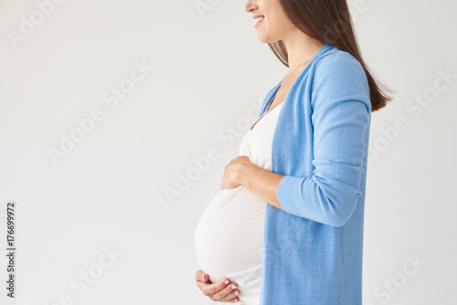 Woman touching pregnant belly against white background