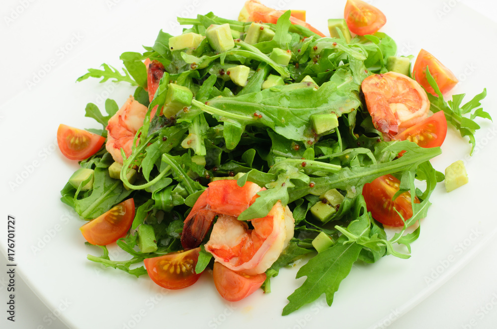 Salad with shrimps, avocado, cherry tomatoes and arugula on a plate isolated on white background Salad with shrimps, avocado, cherry tomatoes and arugula on a plate isolated on white background