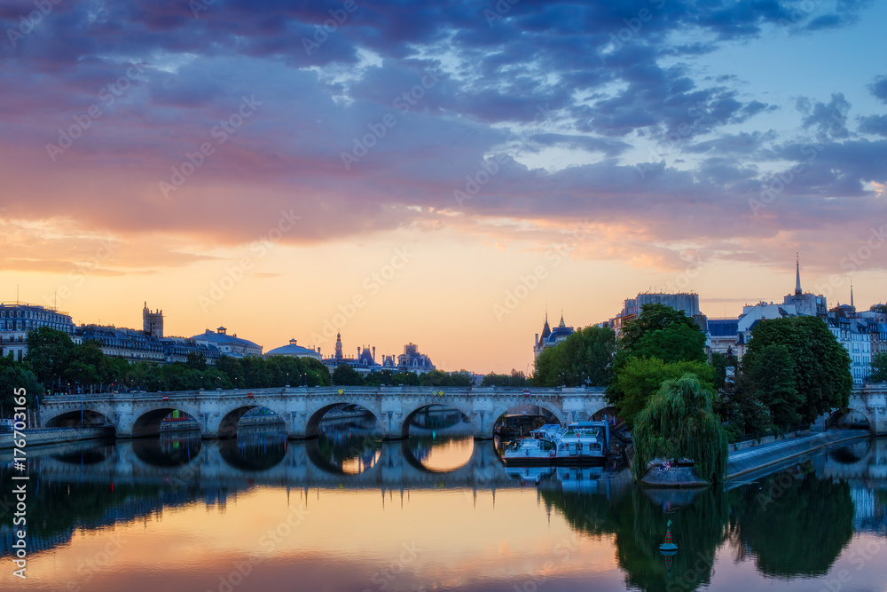 Sunrise over Paris, France with Pont Neuf and the river Seine. Colourful skyline with dramatic clouds.