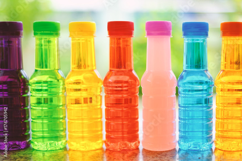 Sweet drinking colorful water bottles arranged in a horizontal row on the table with blurred natural background
