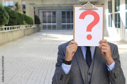 Businessman covering his face with a question mark