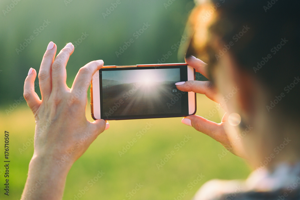 A woman is making a photo on a smartphone.