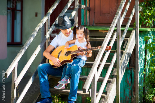 Dad teaches his little daughter the guitar game.